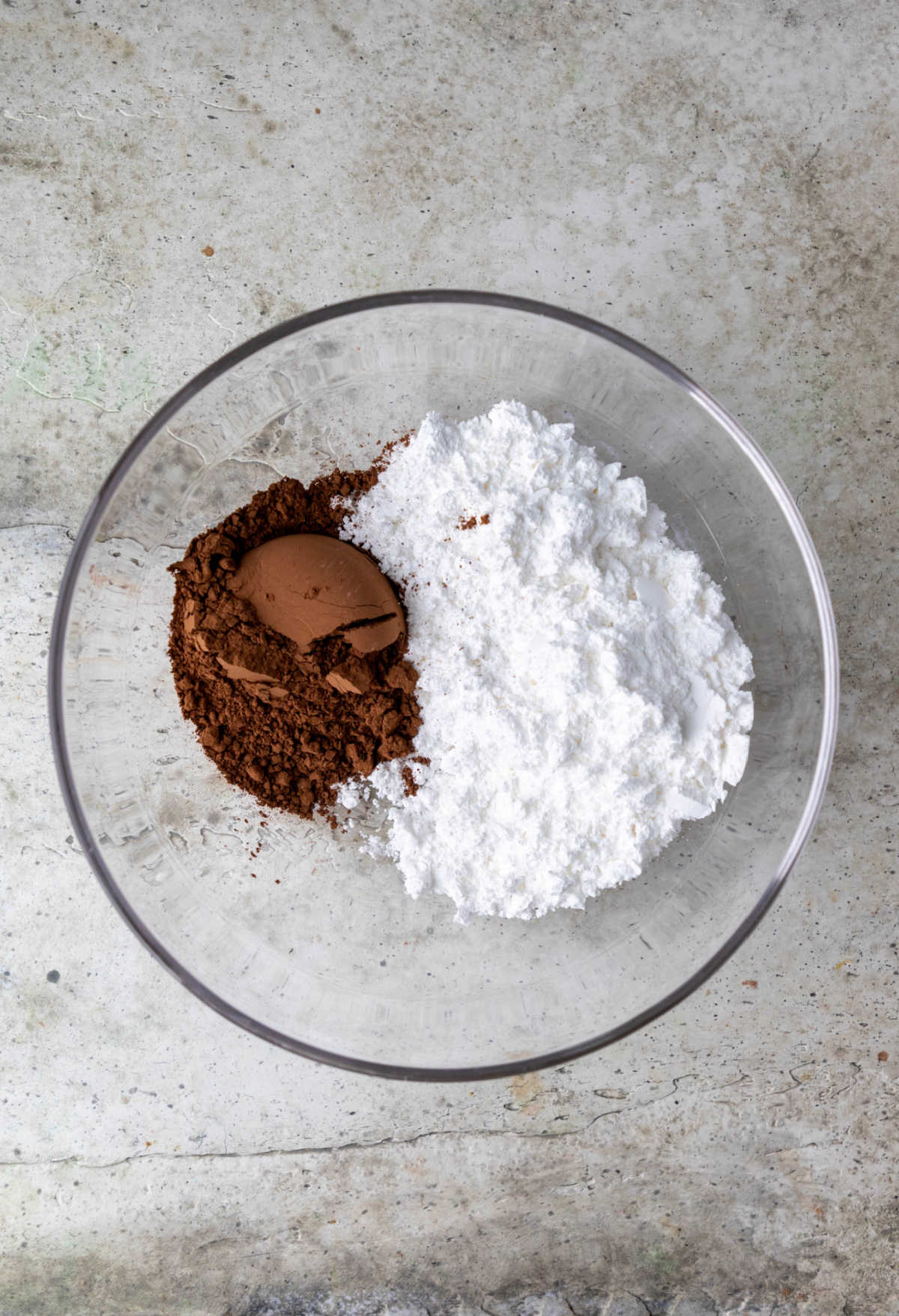 Cocoa powder and powdered sugar in a glass mixing bowl. 