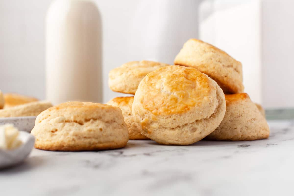 A pile of buttermilk biscuits next to a plate of butter. 