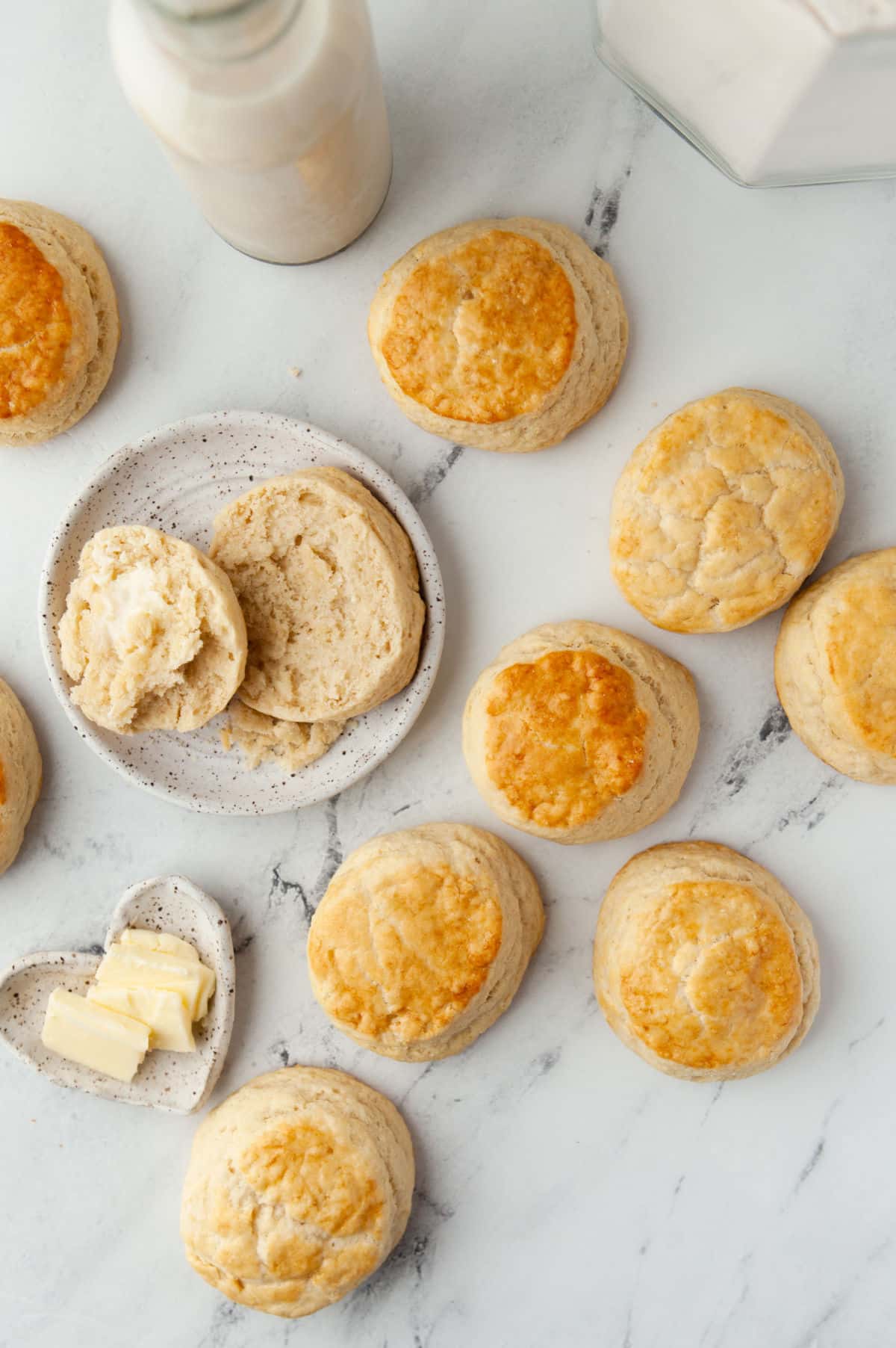 A split buttermilk biscuit on a plate next to rows of biscuits. 