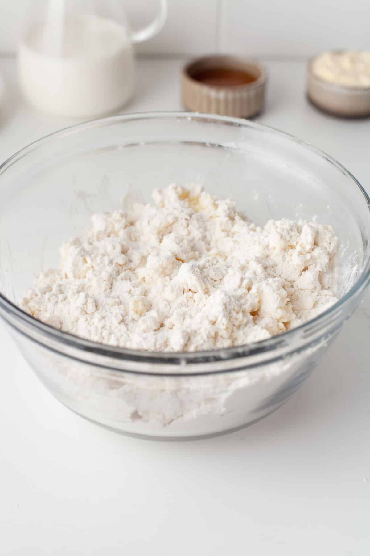 Coarse buttermilk biscuit dough crumbs in a glass mixing bowl. 