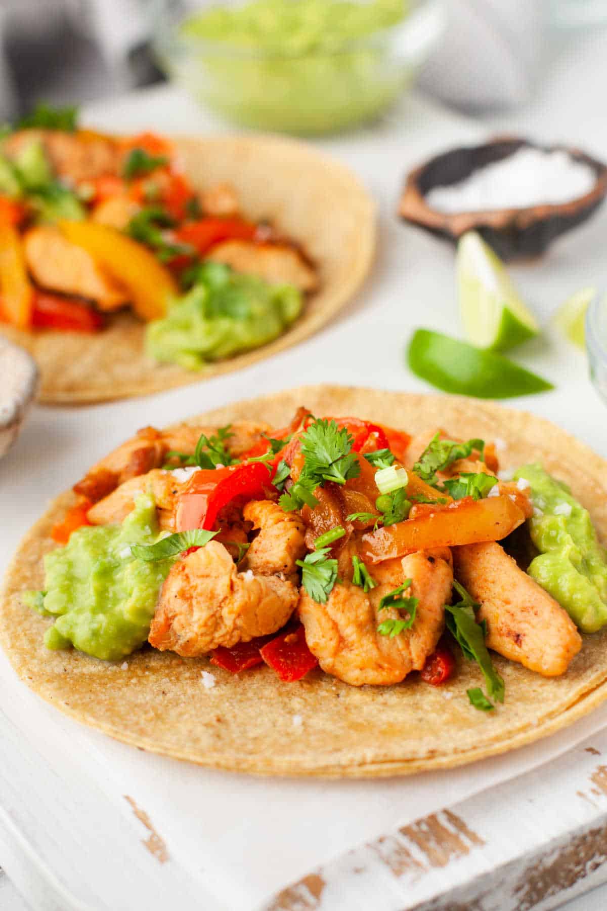Chicken peppers and onions on two flat corn tortillas.