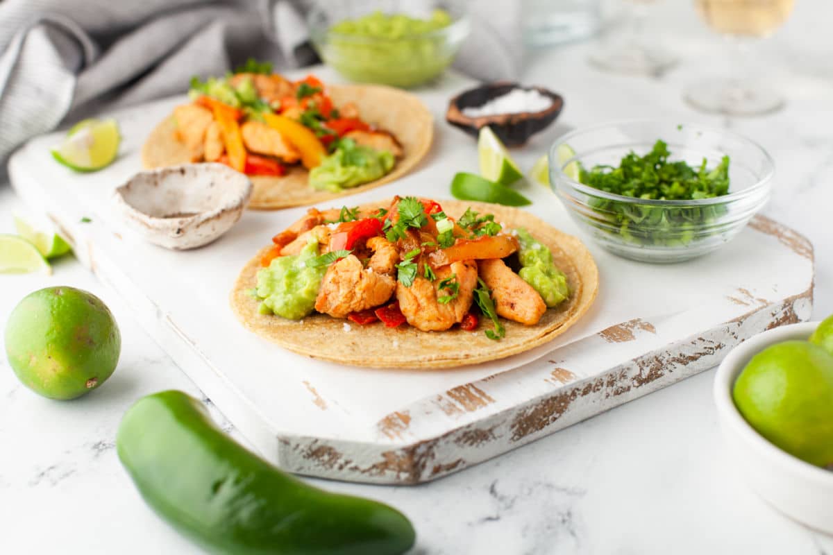 Chicken fajitas surrounded by poblano peppers and limes.