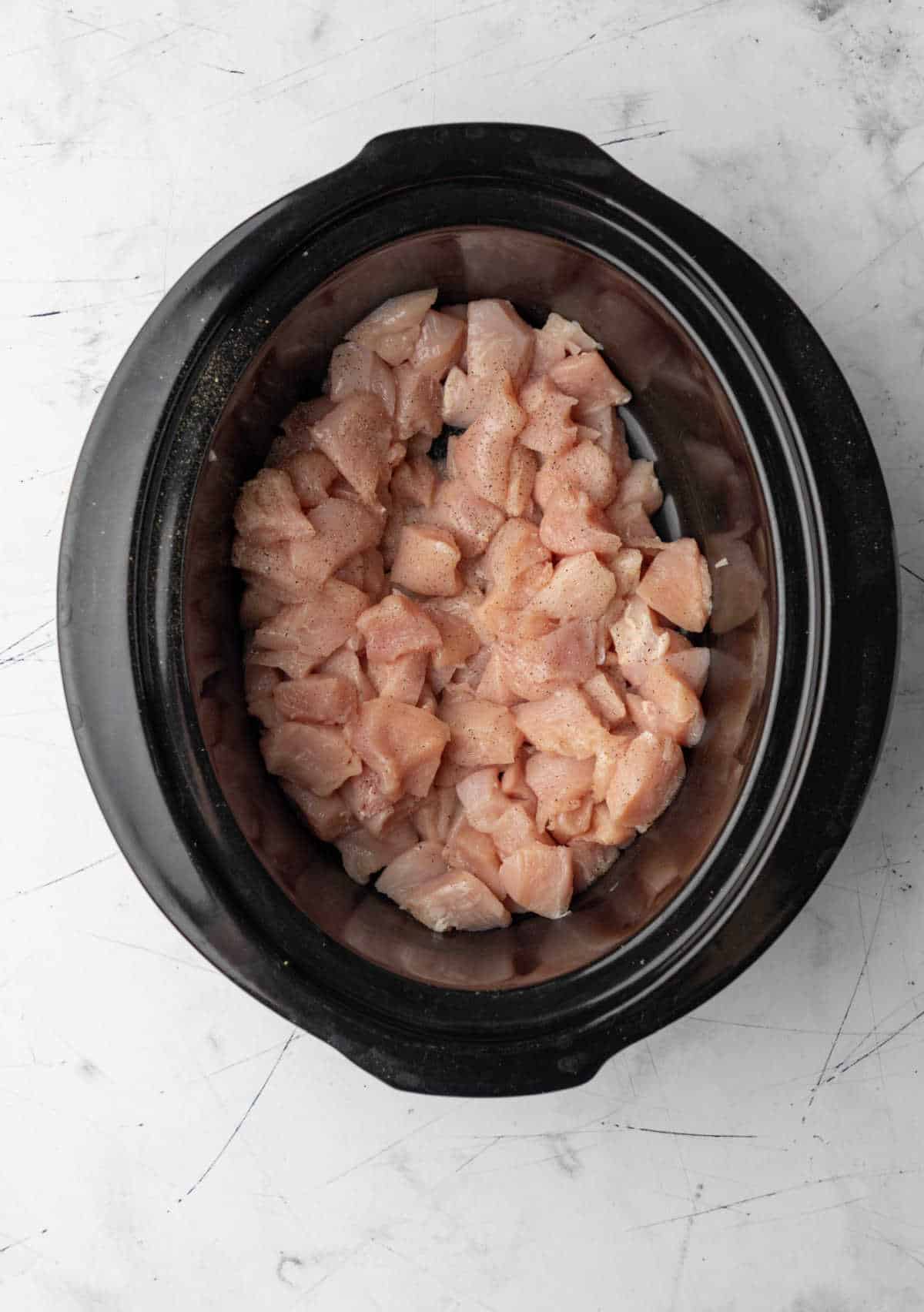 Cut up chicken breast in a slow cooker. 