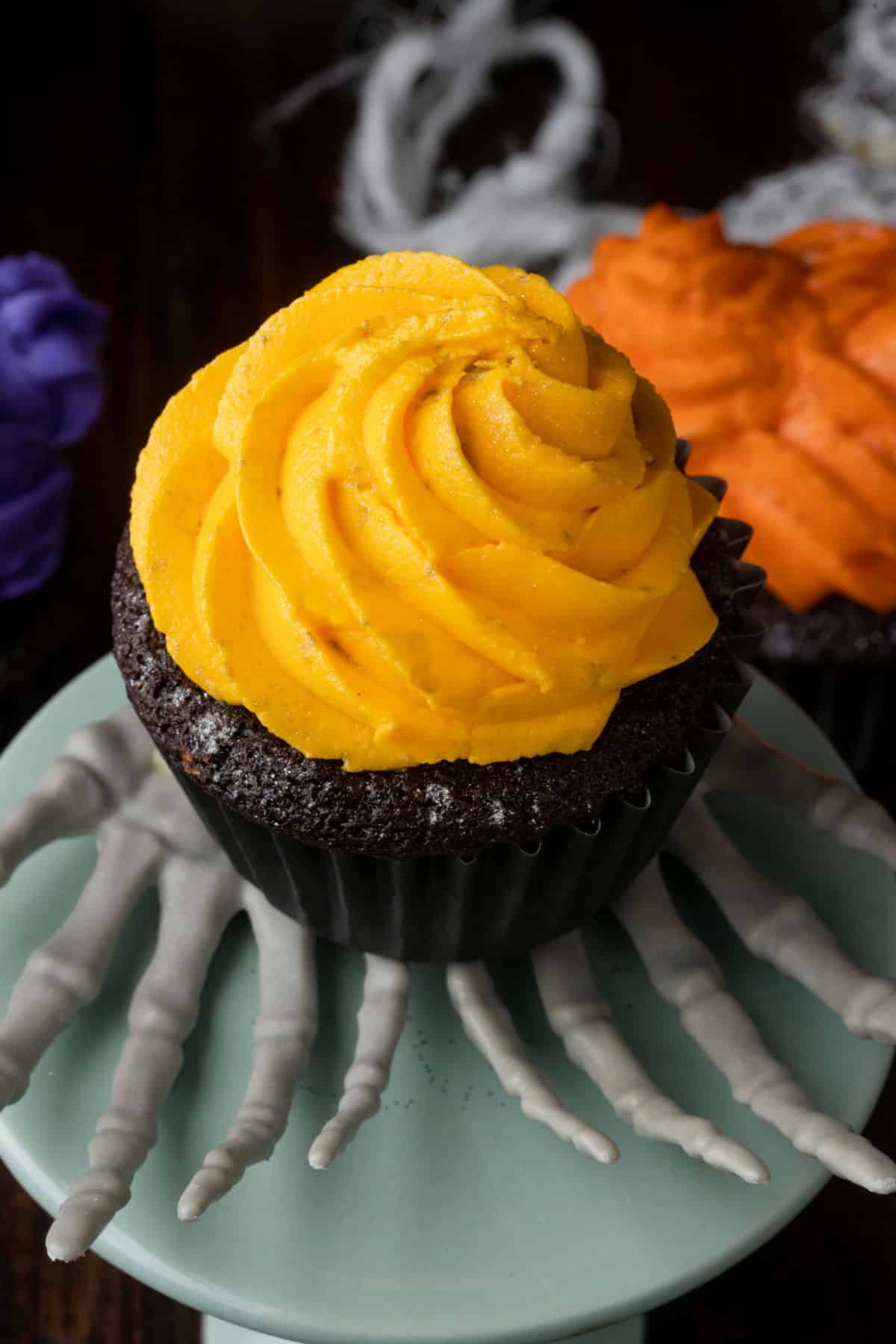 A chocolate cupcake topped with a swirl of yellow frosting. 