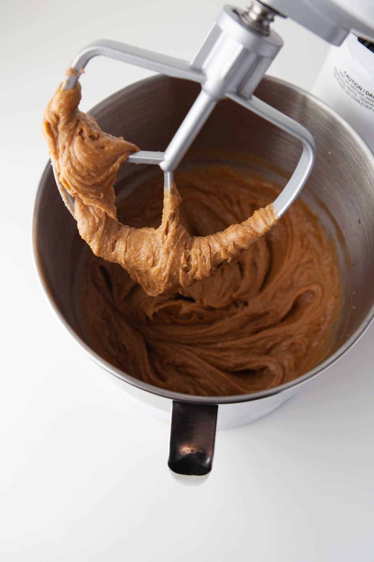 A paddle beater attachment with peanut butter egg mixture on it. 