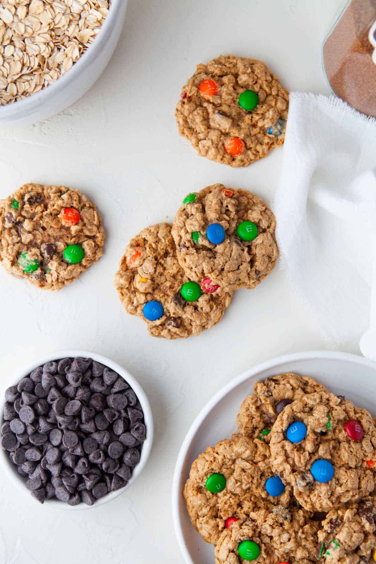 A plate of monster cookies next to a bowl of chocolate chips. 