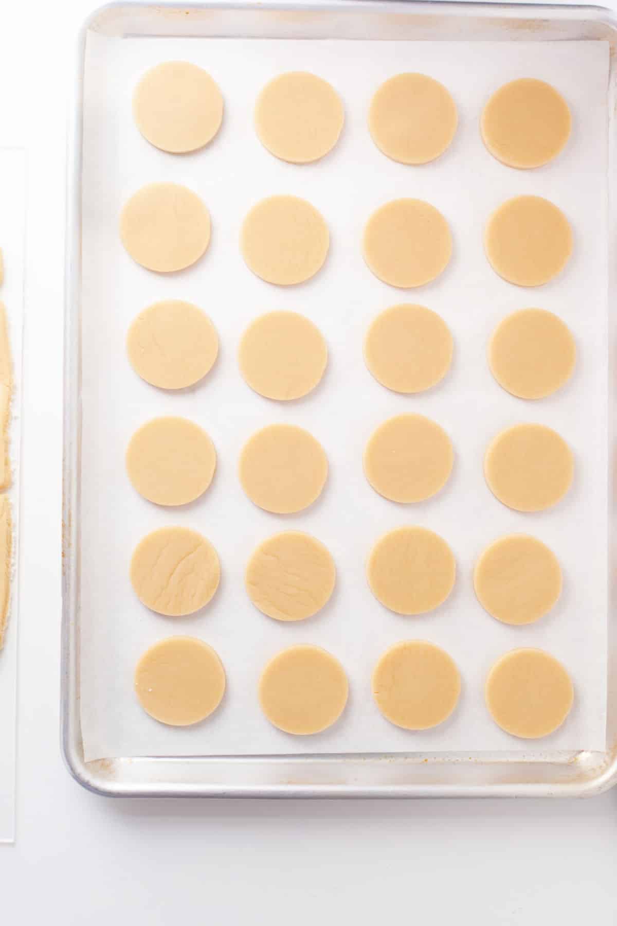 Cut out sugar cookie dough on a parchment lined tray.
