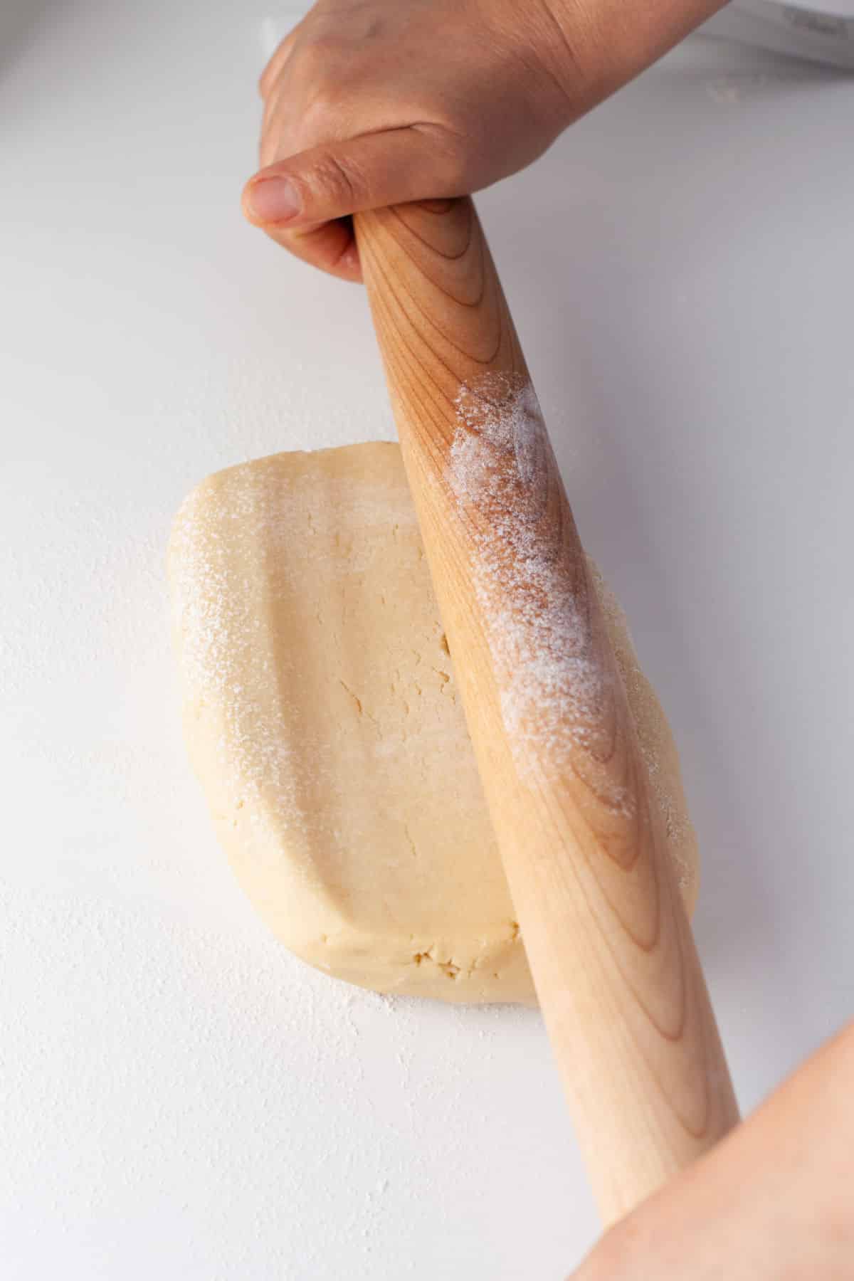 A rolling pin rolling out sugar cookie dough. 