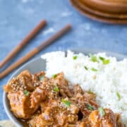 Slow Cooker Sesame Chicken and rice in a grey dish next to a pair of chopsticks.