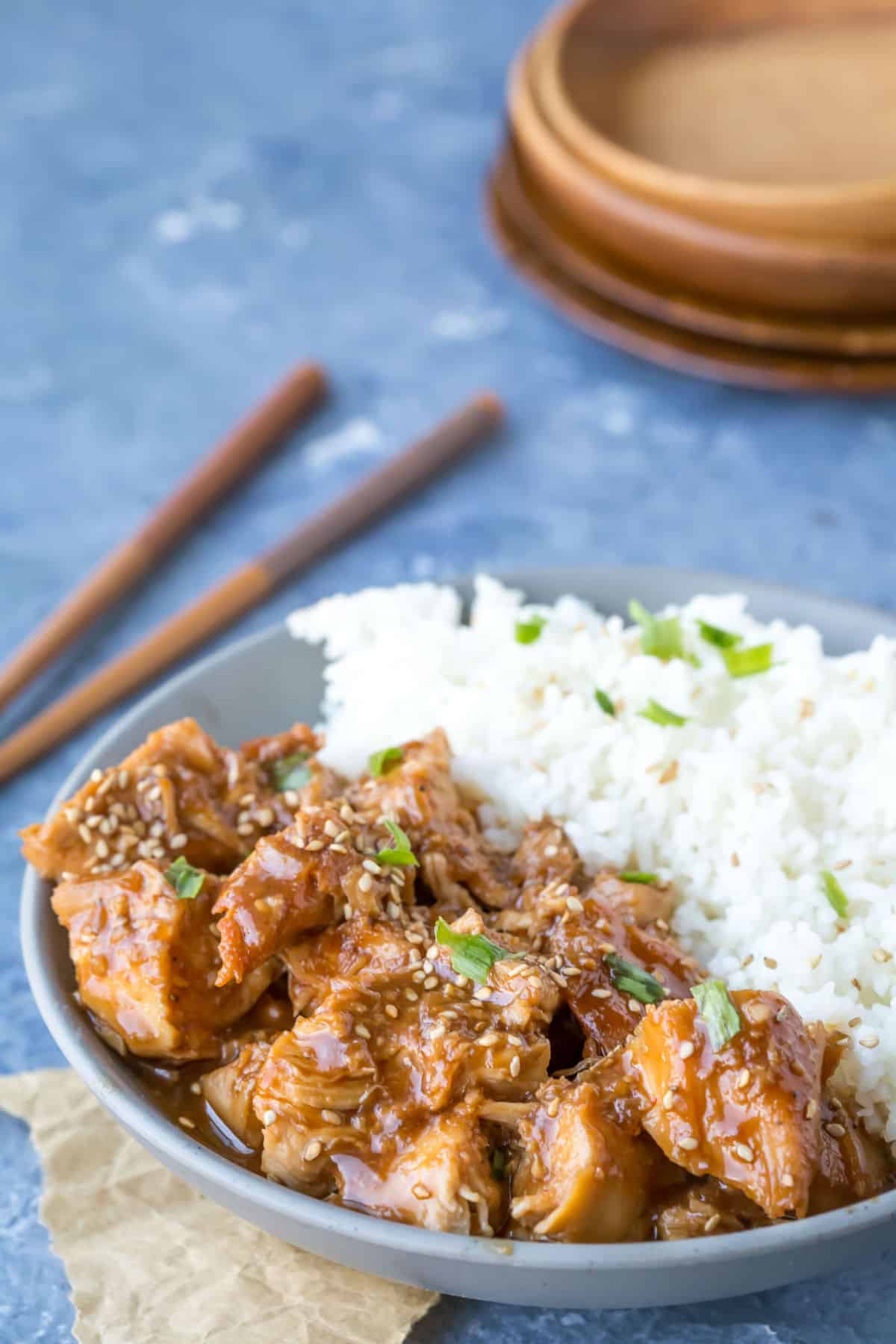 Slow Cooker Sesame Chicken and rice in a grey dish next to a pair of chopsticks.