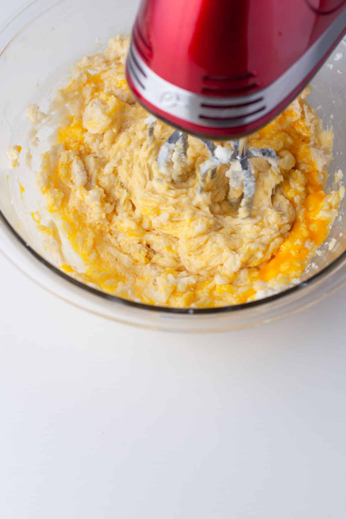 Eggs and vanilla mixing into a creamed butter mixture.
