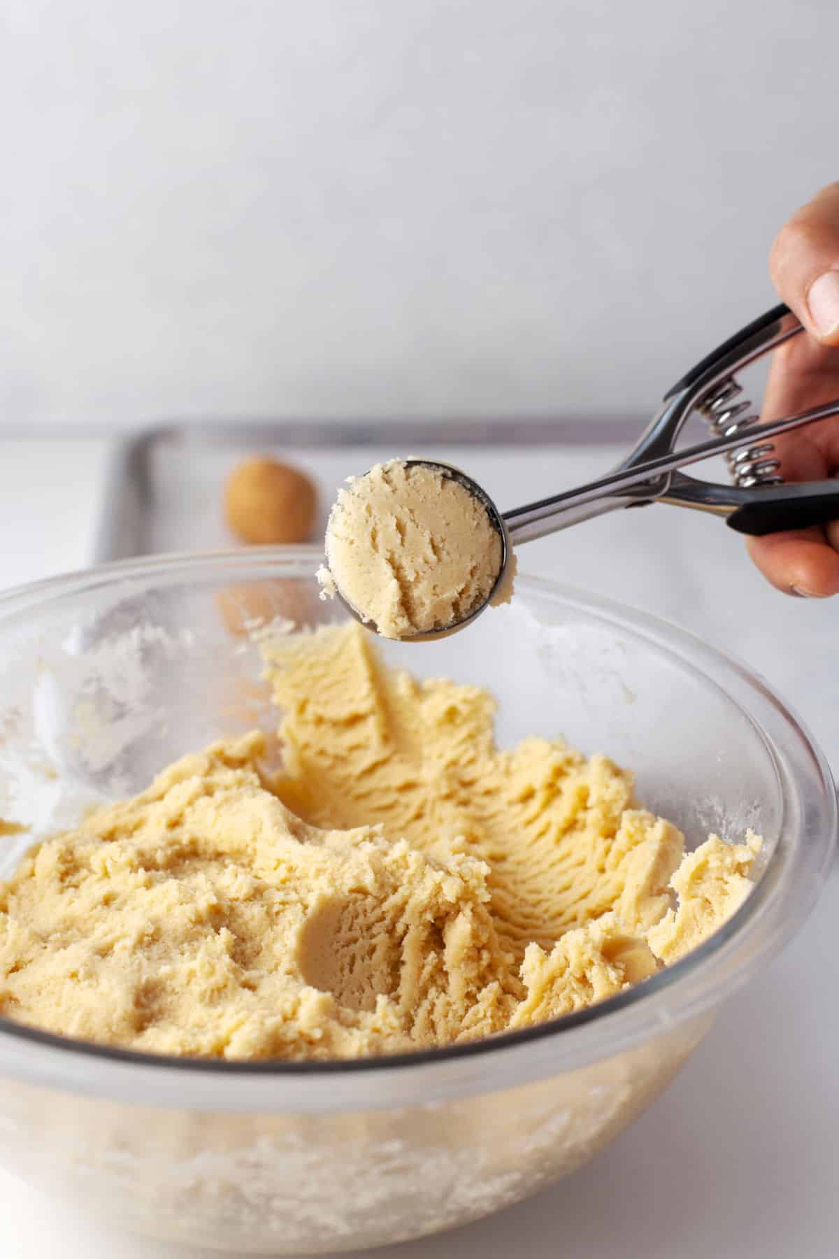 A cookie scoop holding a scoop of snickerdoodle cookie dough.