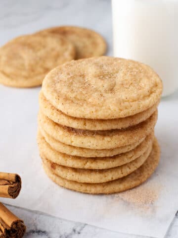 Stack of snickerdoodle cookies next to a bottle of milk.