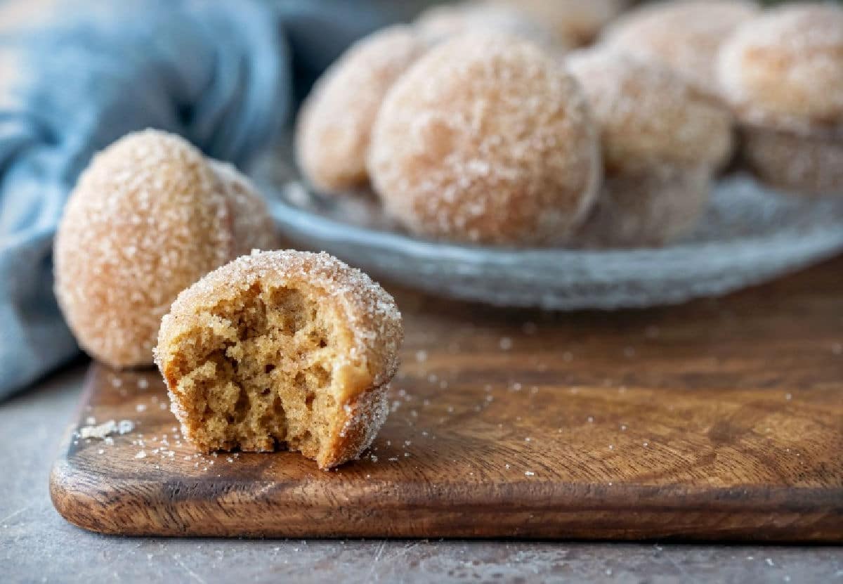 An apple cider donut muffin next to a plate of donut muffins.