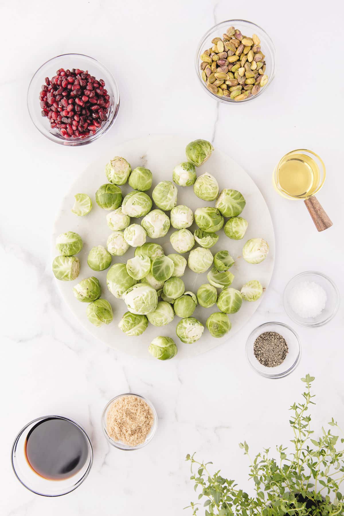 Ingredients for roasted Brussels sprouts in dishes on a marble background. 