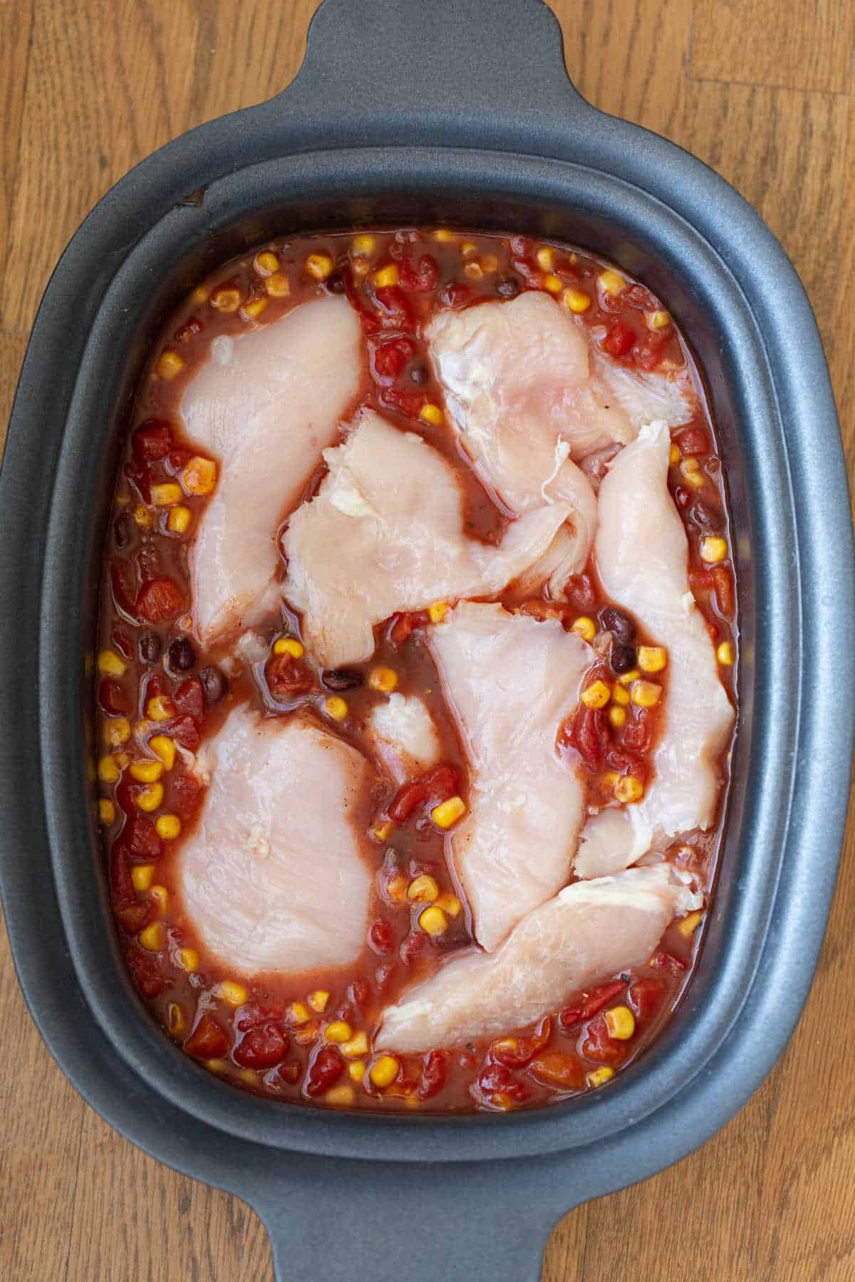 Chicken breast in chili ingredients in a slow cooker. 
