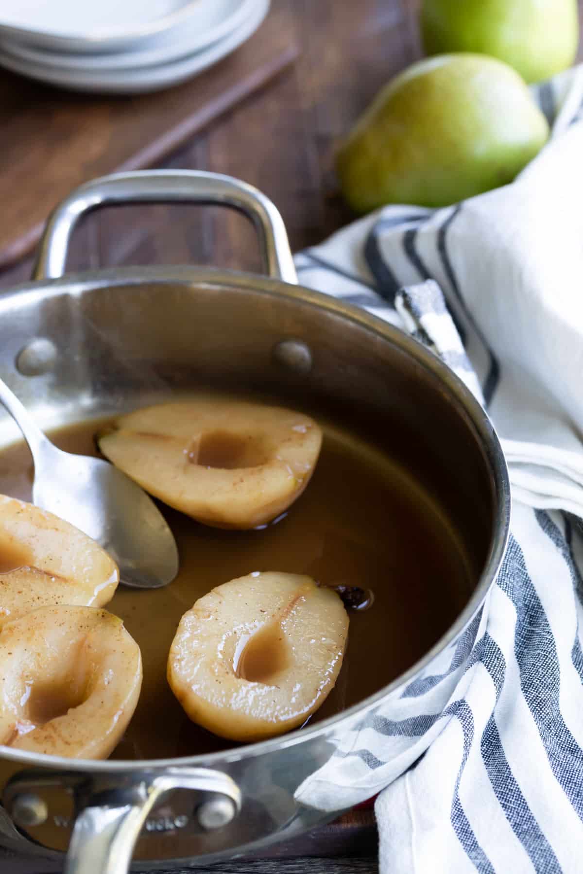 Poached pears in cider in a saucepan. 