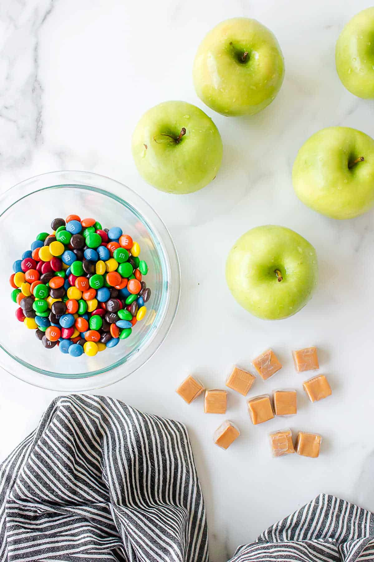 Ingredients for M&M caramel apples in dishes.