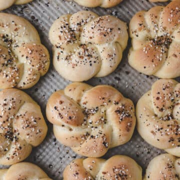 Three rows of everything bagel knots on a baking pan.