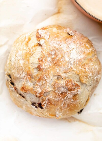 A loaf of no knead cranberry bread next to a Dutch oven.