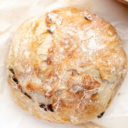 A loaf of no knead cranberry bread next to a Dutch oven.