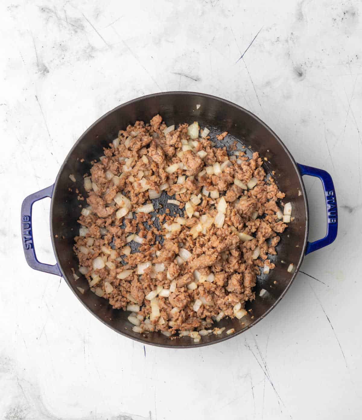Diced onion and sausage in a skillet.