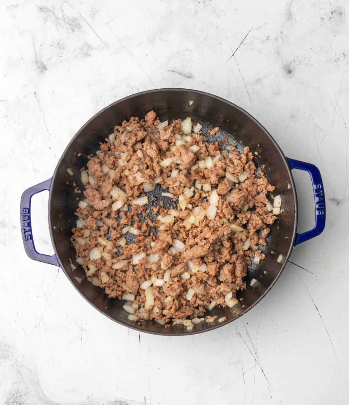 Diced onion and sausage in a skillet. 