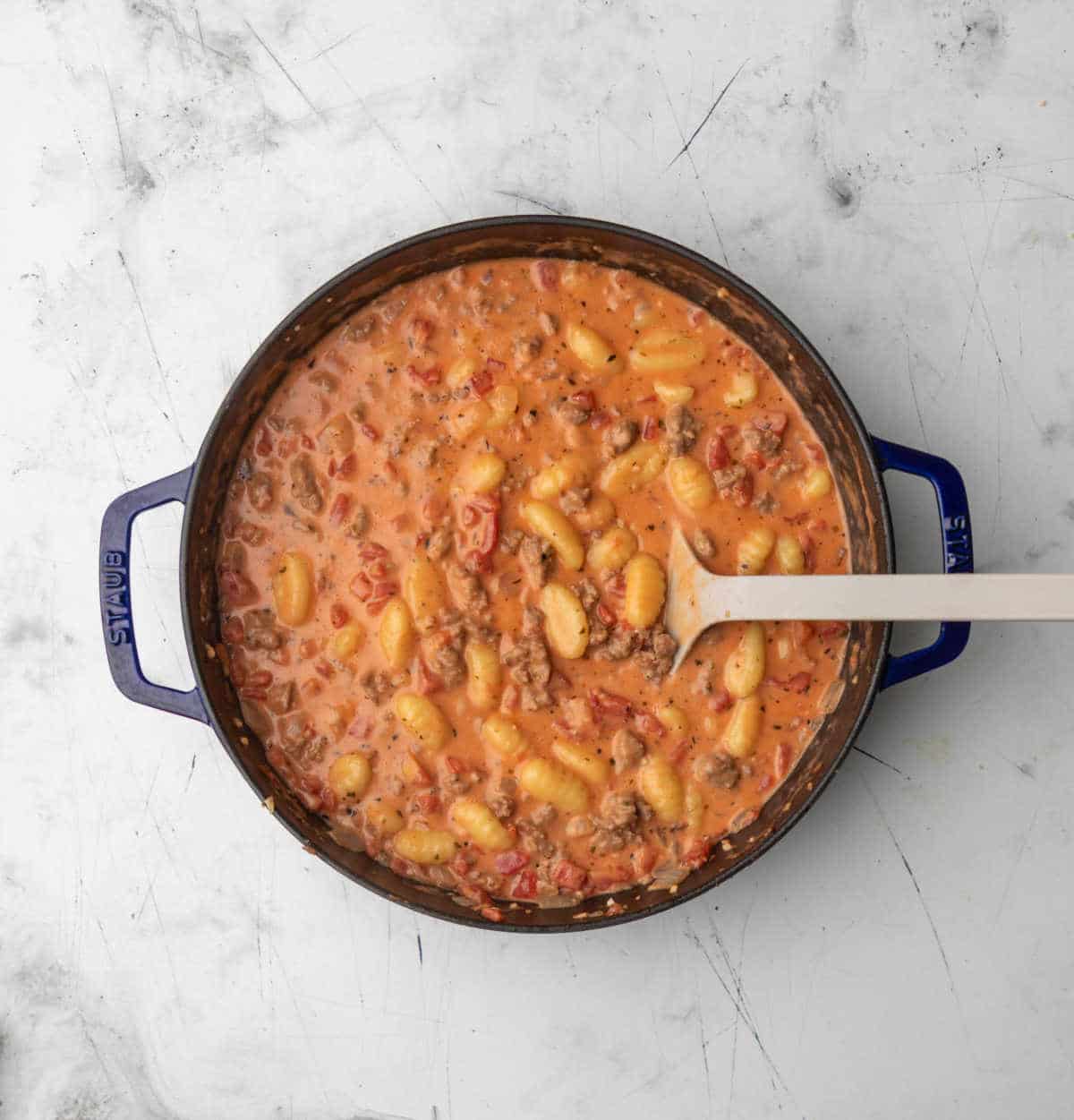 Gnocchi and sausage in tomato cream sausage in a skillet.