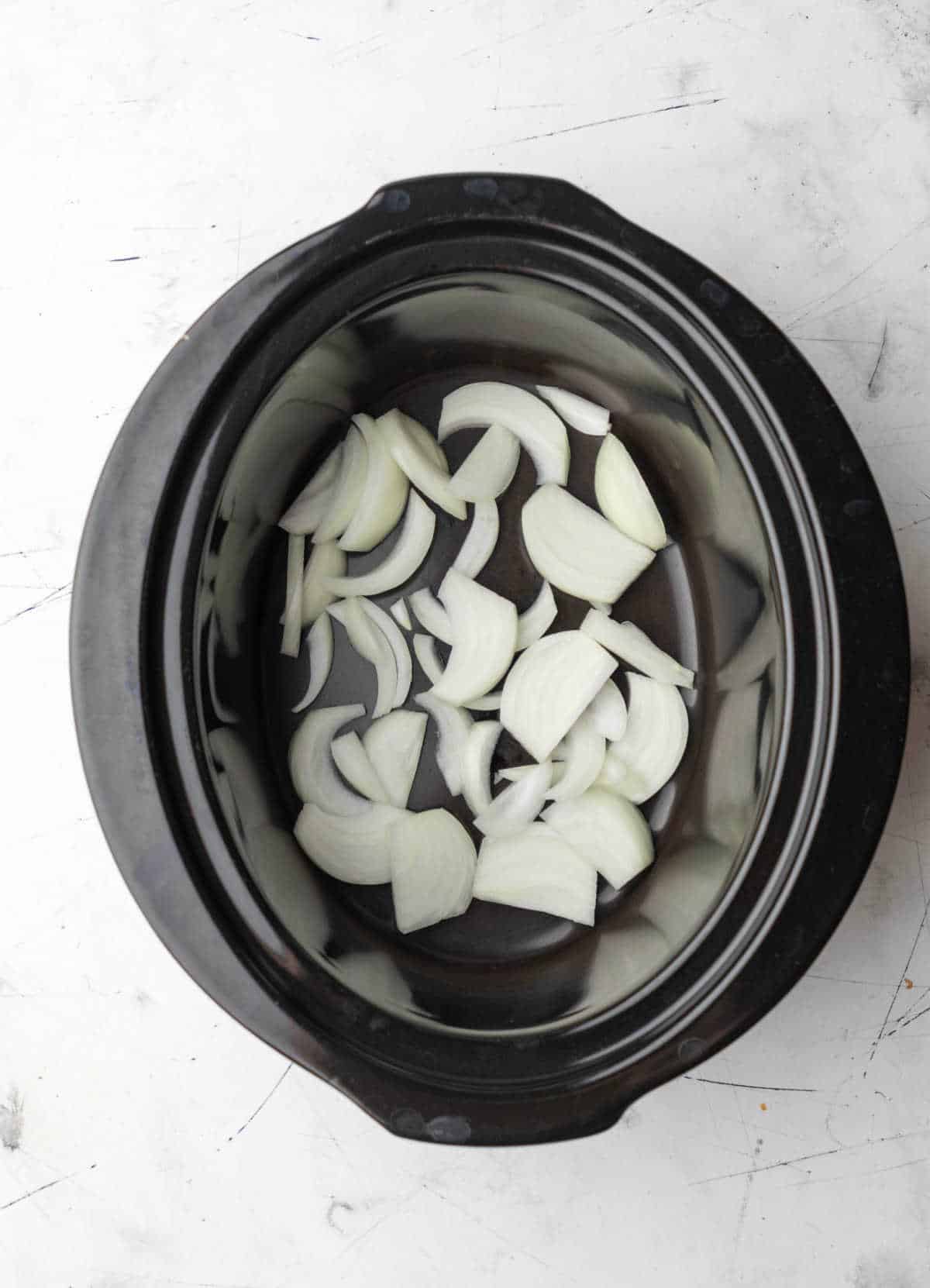 Sliced onions in a dreary cooker insert.   Leisurely Cooker Barbecue Pork slow cooker bbq beef 11 1200