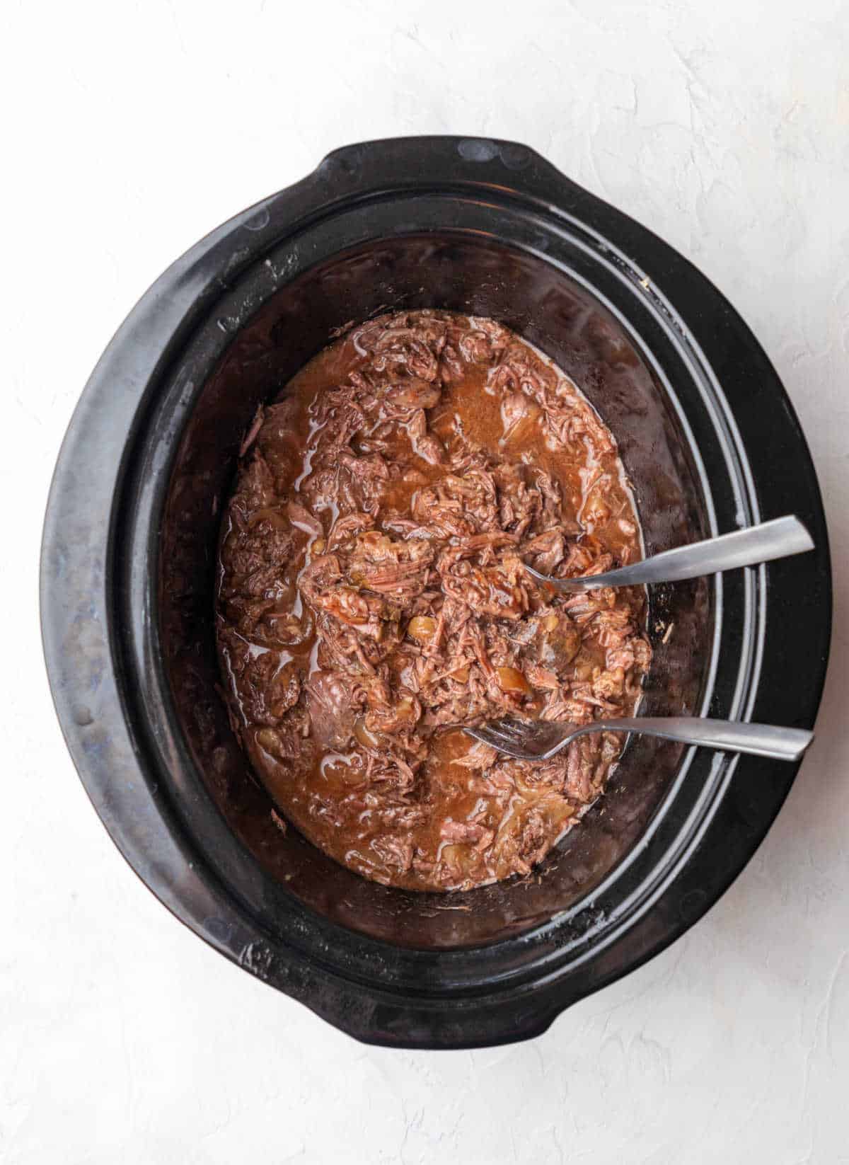 Shredded beef in barbecue sauce in a crock pot. 