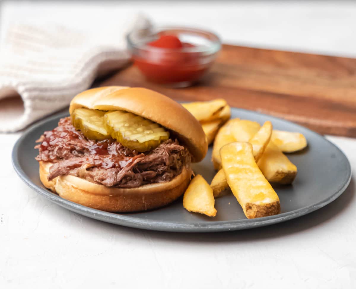 A barbecue beef sandwich topped with pickles. 