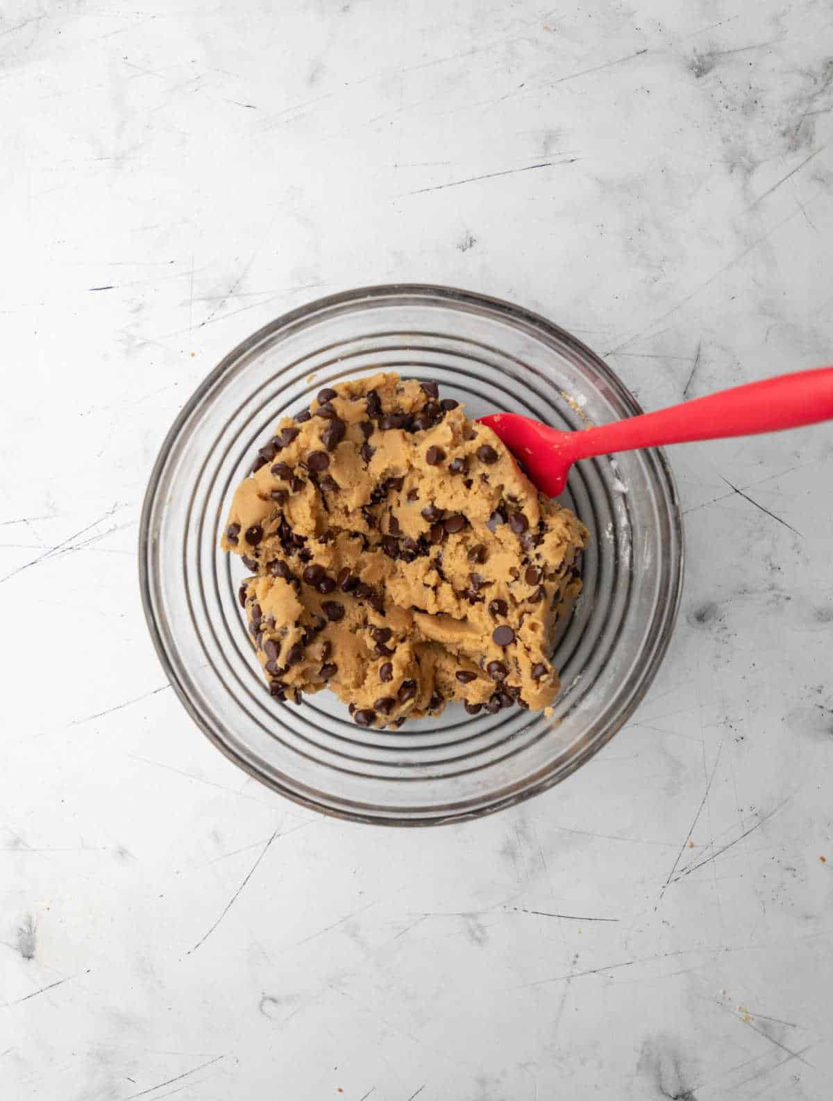 Chocolate chip cookie dough in a glass mixing bowl. 