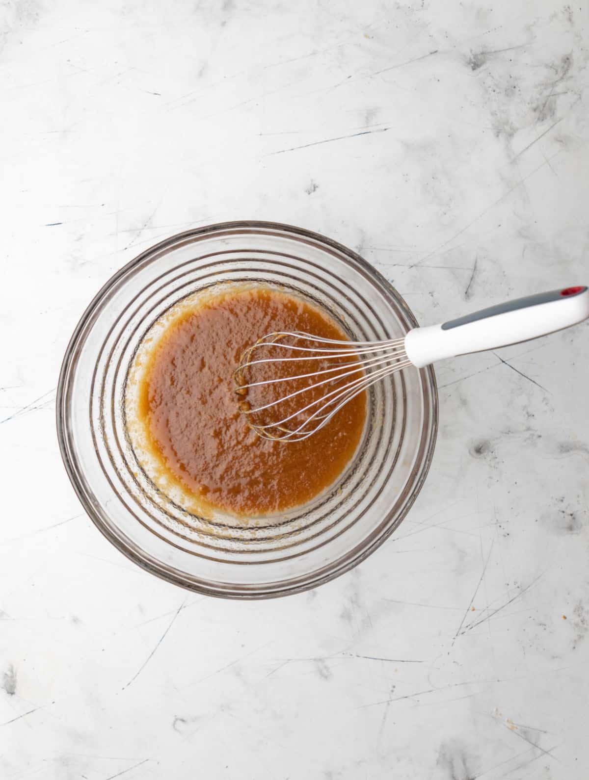 Butter and sugars mixed together in a glass mixing bowl. 