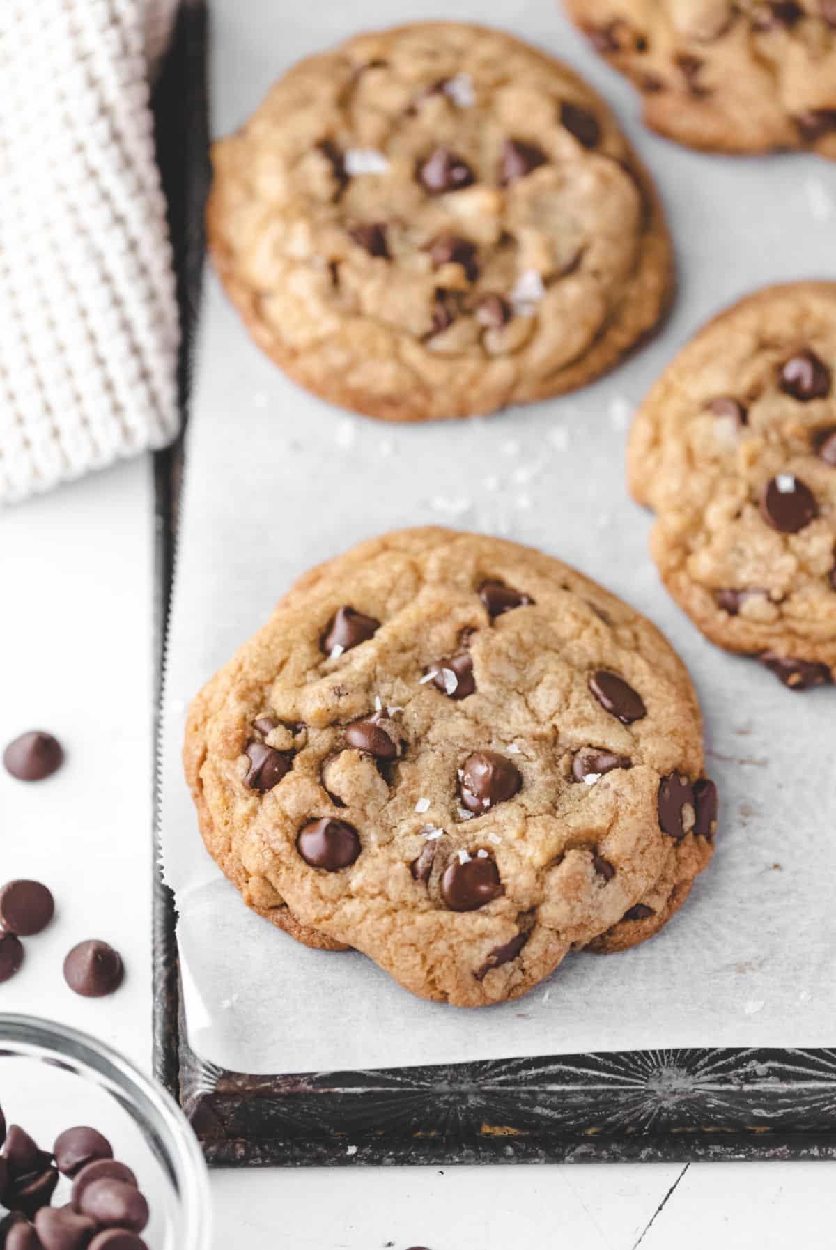 Two thick chocolate chip cookies in a row on a piece of parchment paper. 