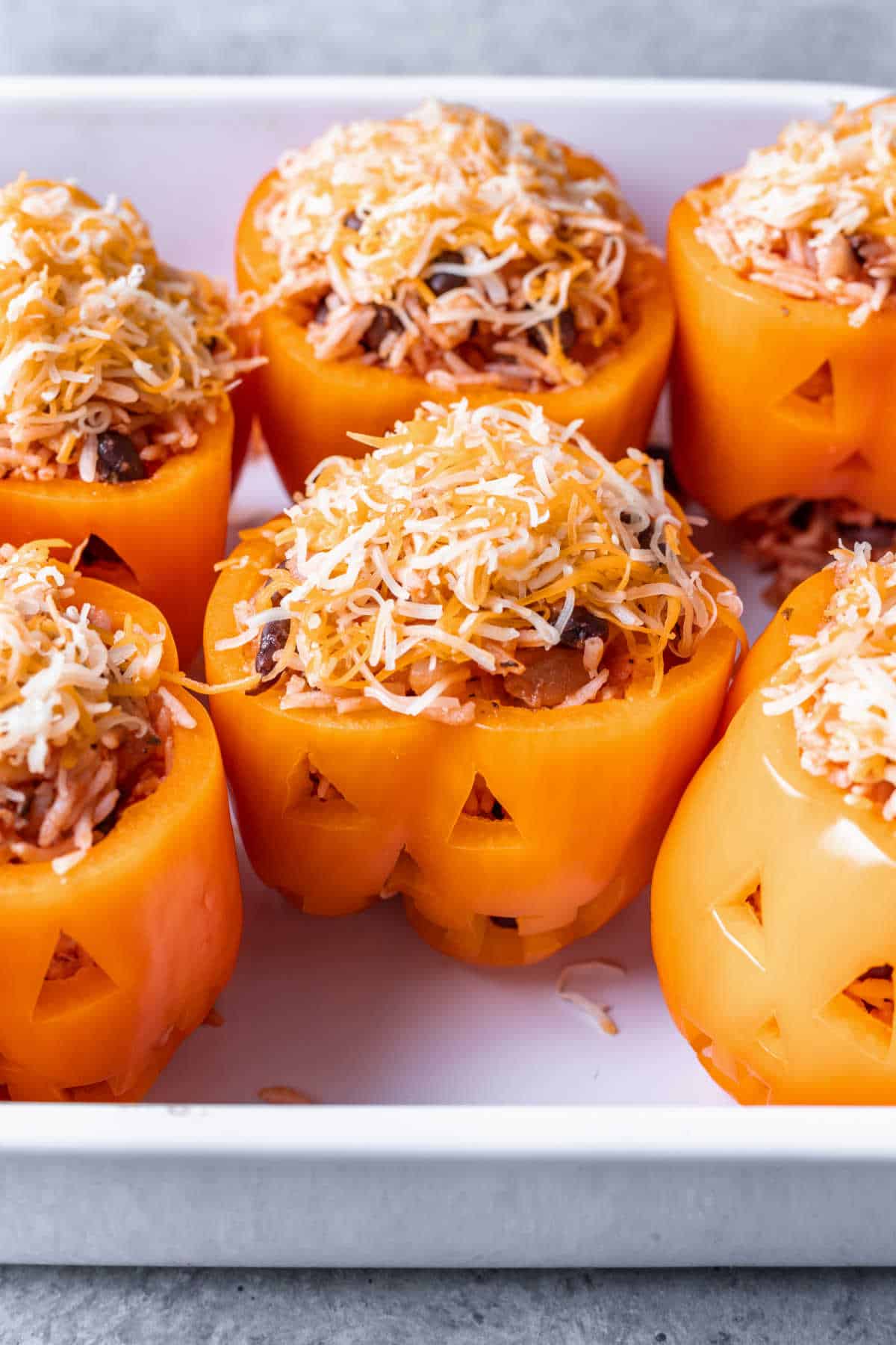 Shredded cheese on top of Halloween stuffed peppers.