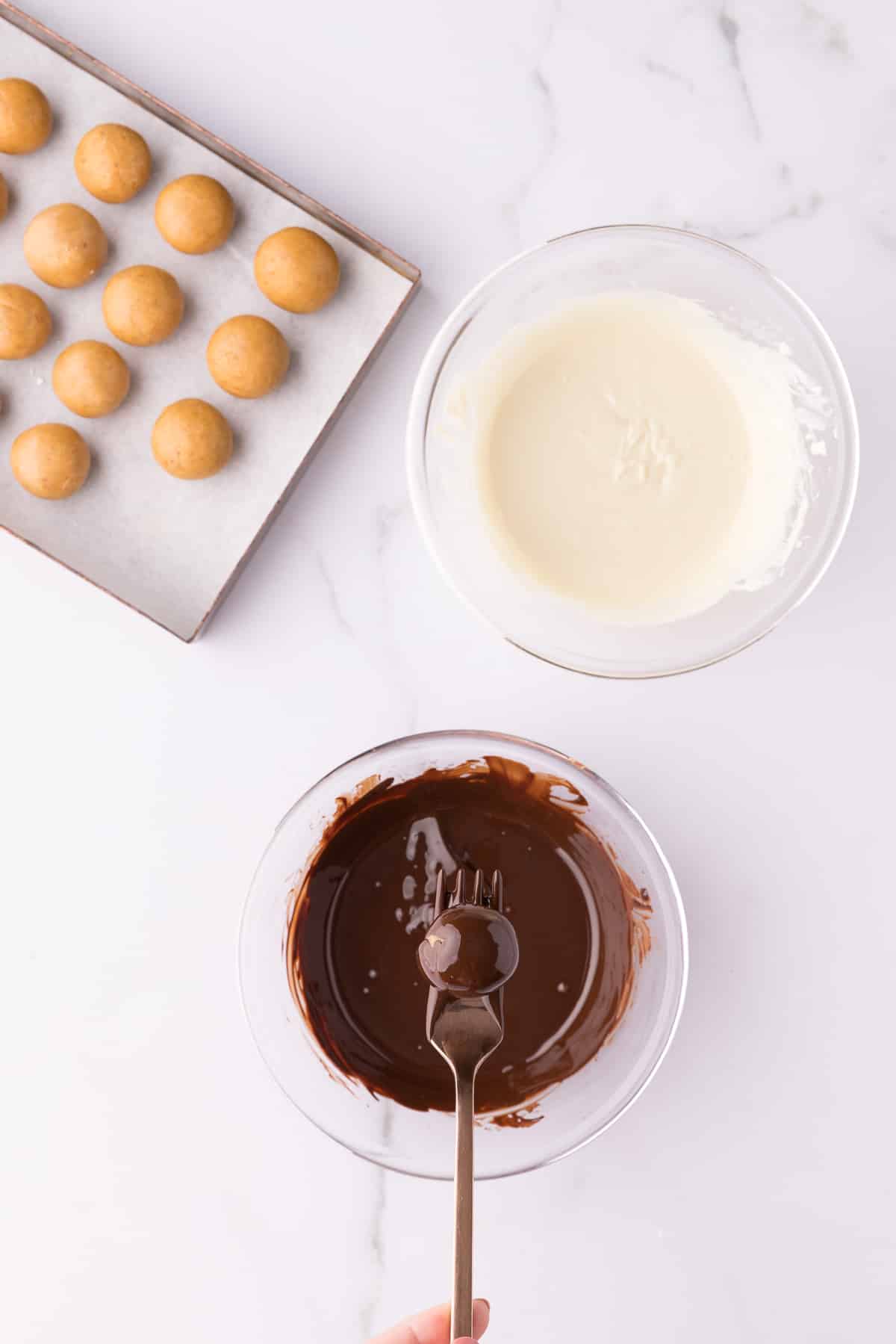 A fork holding up a dipped pumpkin pie truffle over a bowl of melted chocolate. 