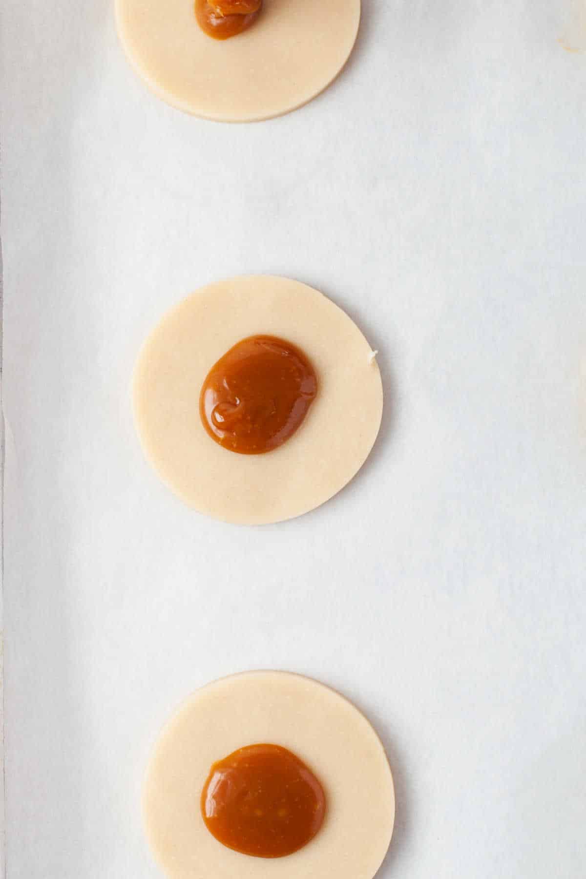 A dollop of caramel in the center of a piece of pie dough. 