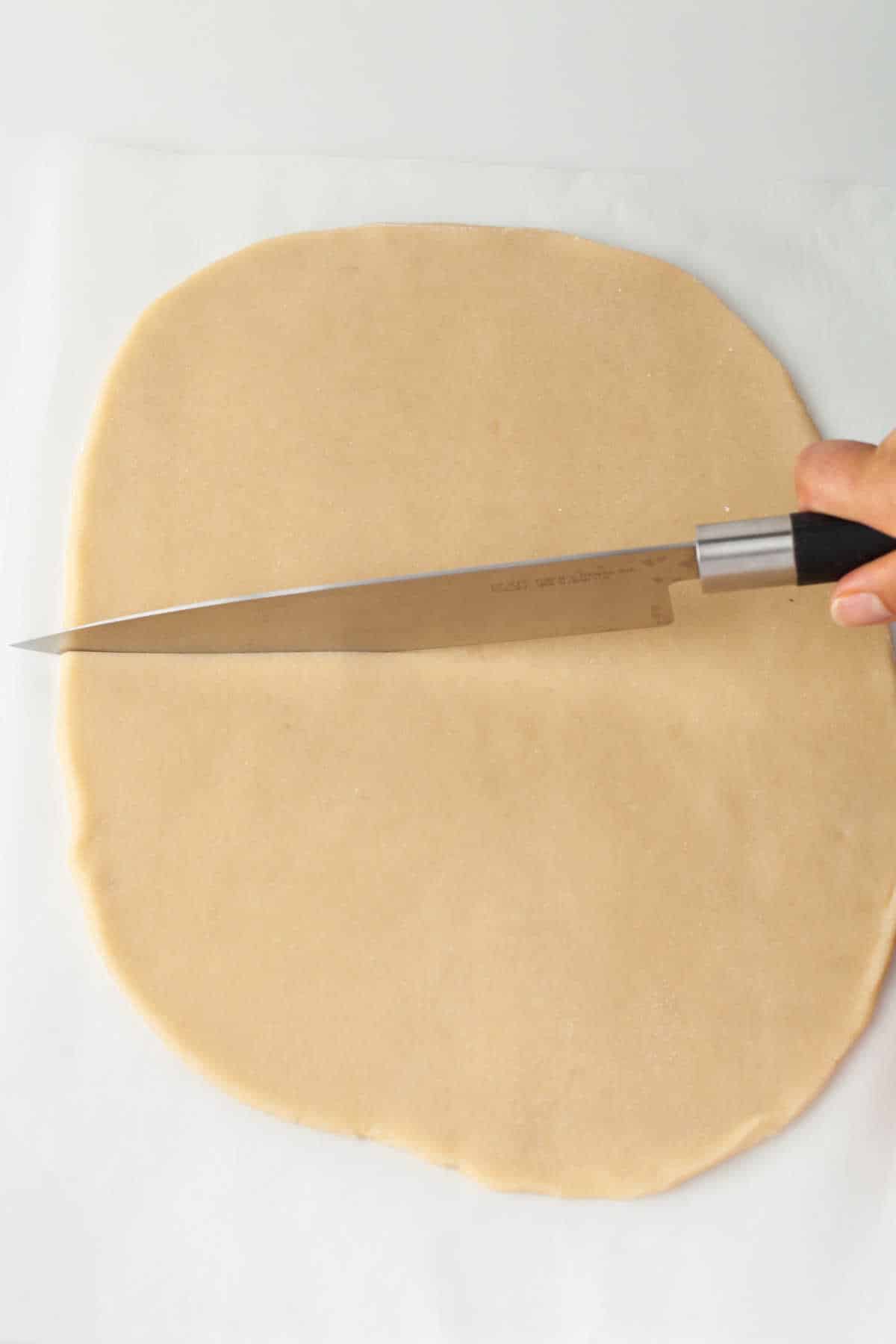 A knife cutting strips of dough. 