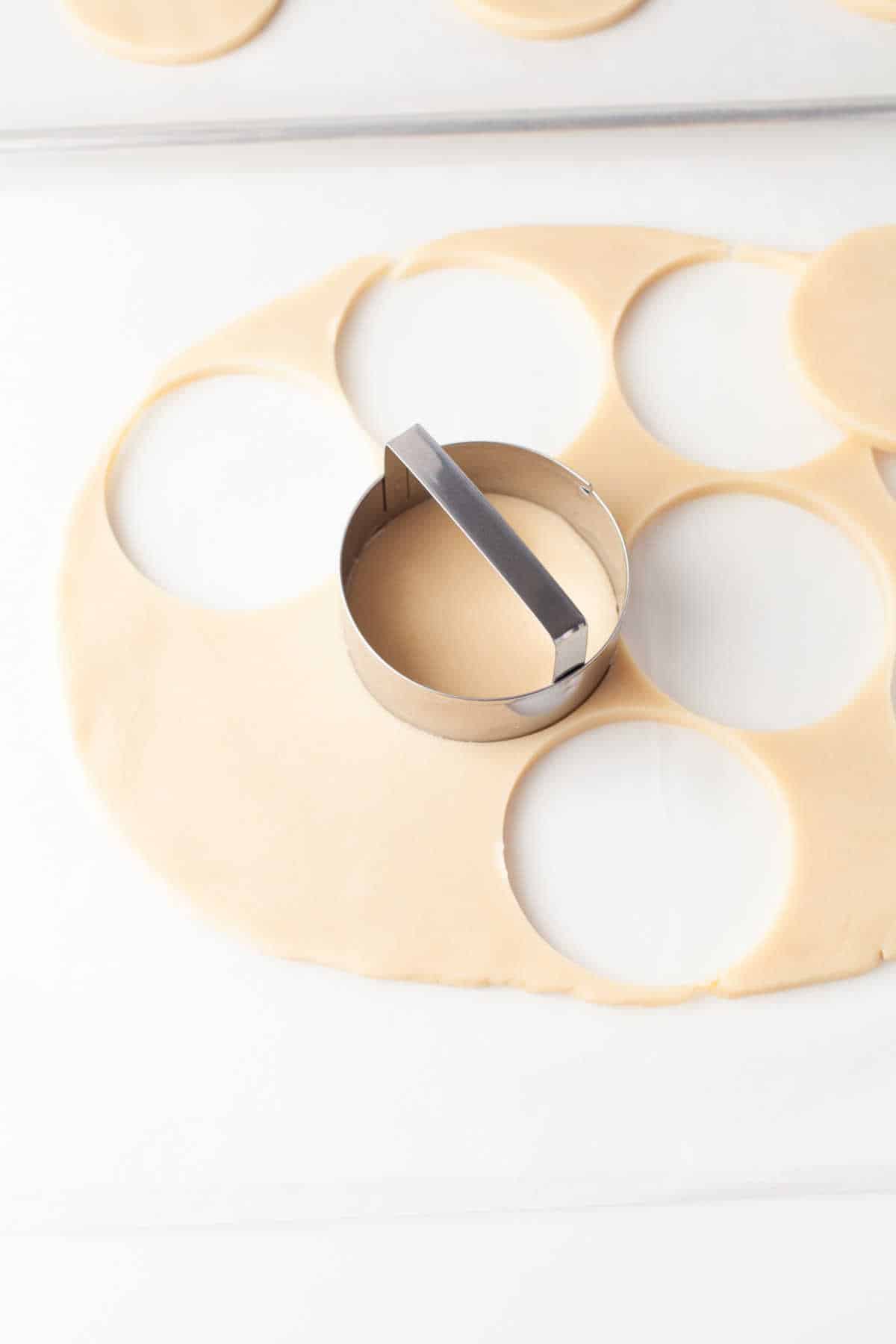 A round cookie cutter cutting circles of dough out. 