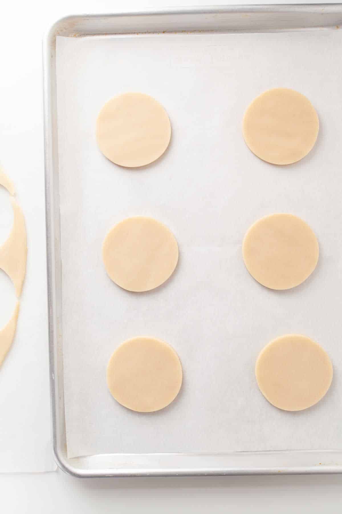 Circles of pie dough on a baking sheet. 