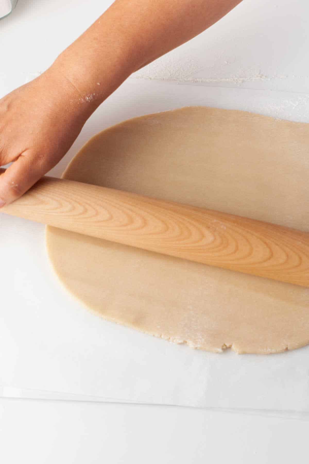 A rolling pin rolling out pie dough. 