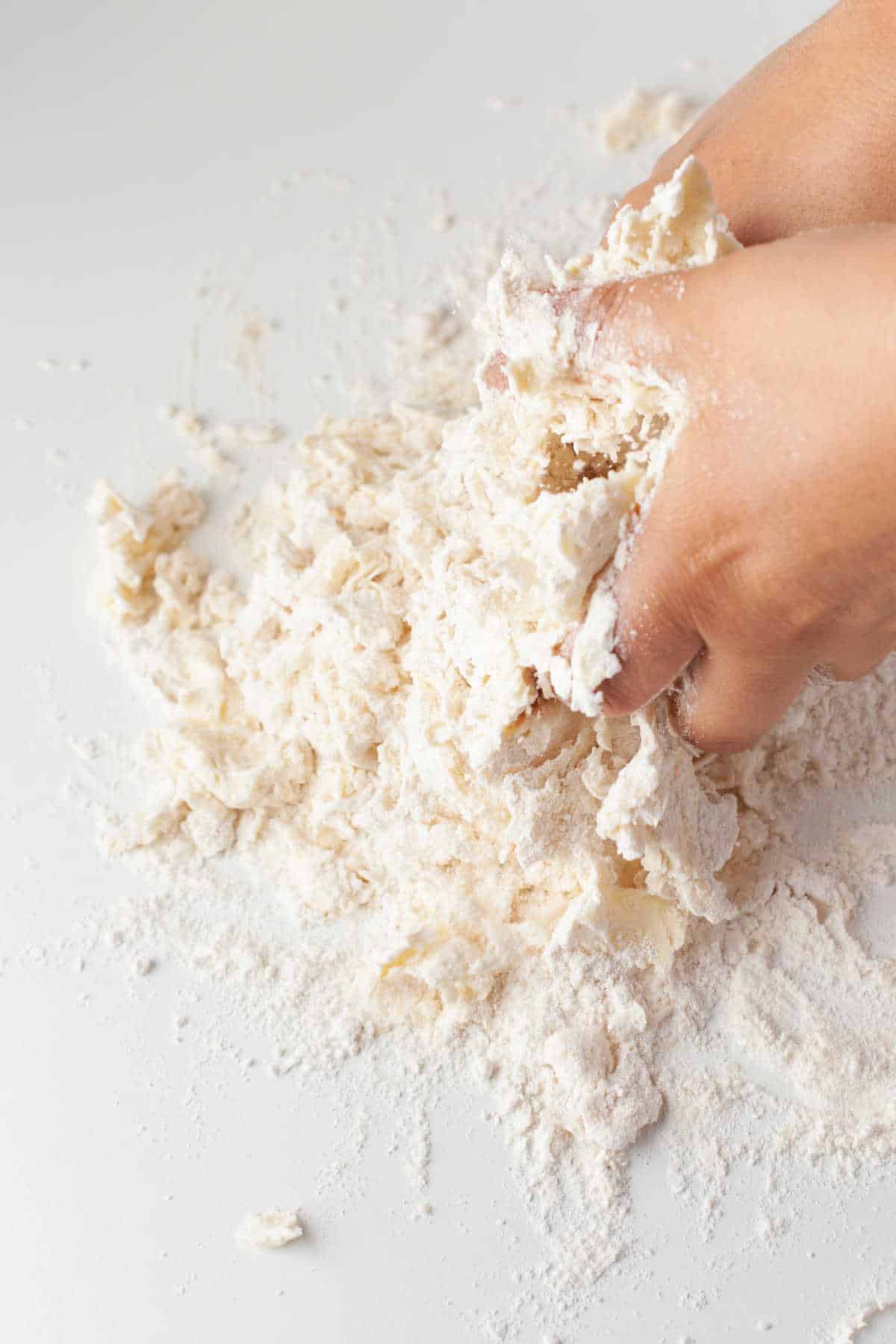 Hands mixing butter into flour and salt. 