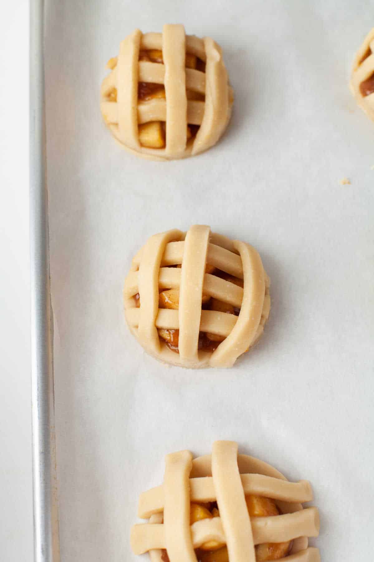 Unbaked apple pie cookies on a baking sheet. 