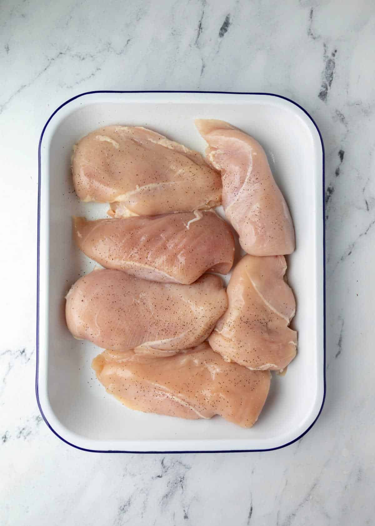 Raw chicken breast in a 9 by 13 pan. 