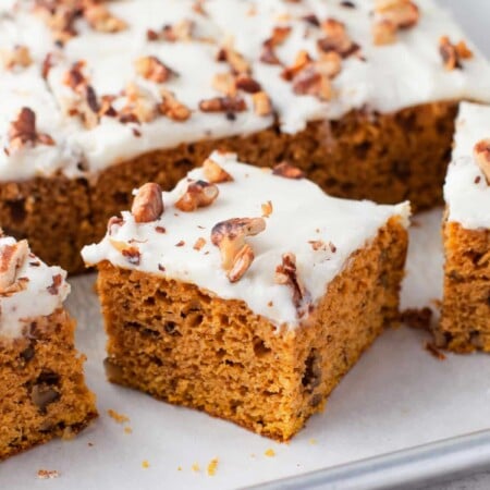 A pumpkin bar cut an at an angle next to the tray of pumpkin bars.