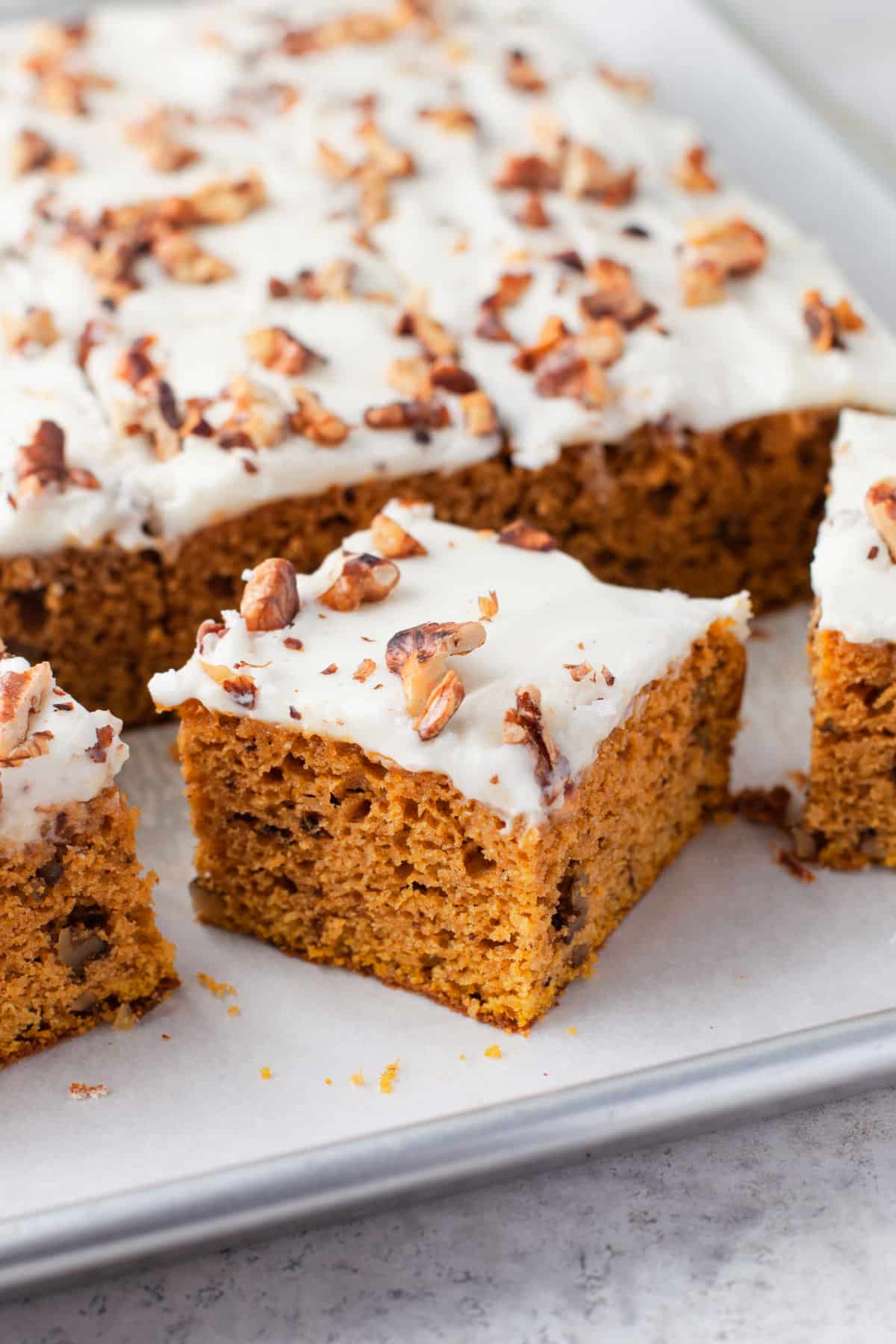 A pumpkin bar cut an at an angle next to the tray of pumpkin bars.