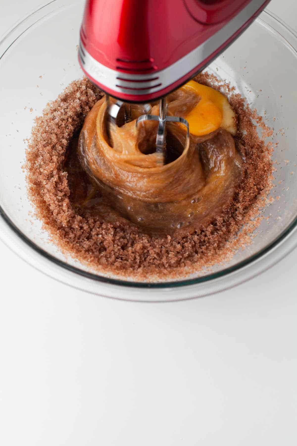 Hand mixer beating eggs into oil and sugar mixture. 