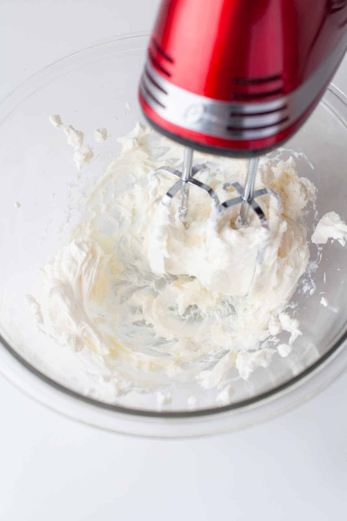 Hand mixer beating butter and cream cheese together. 