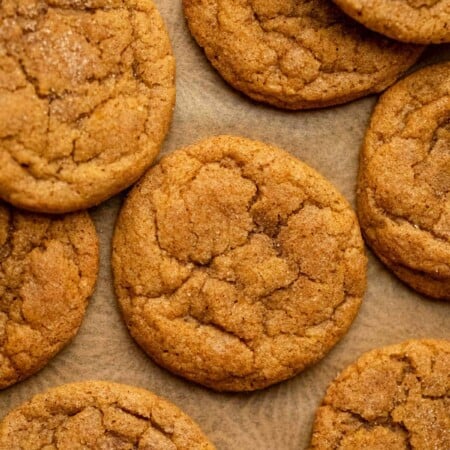 Overlapping pumpkin snickerdoodles on a piece of brown parchment paper.