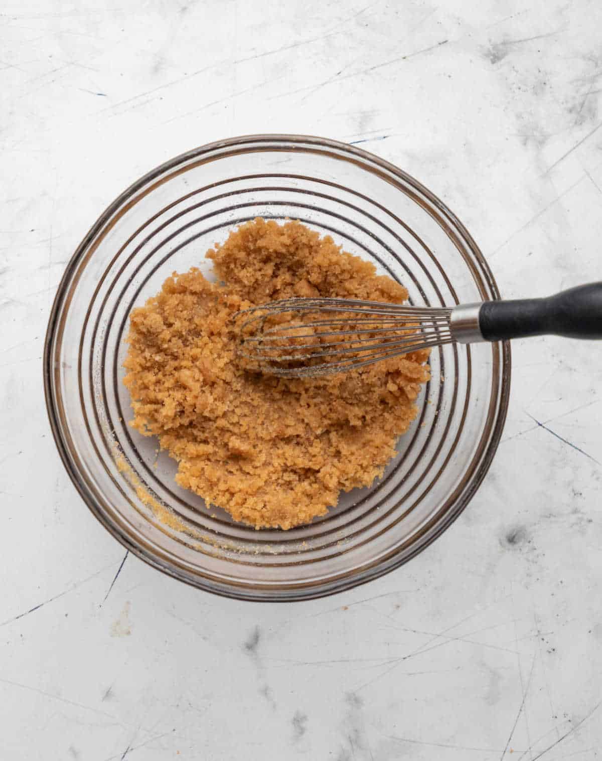 White and brown sugar whisked into brown butter in a glass mixing bowl. 